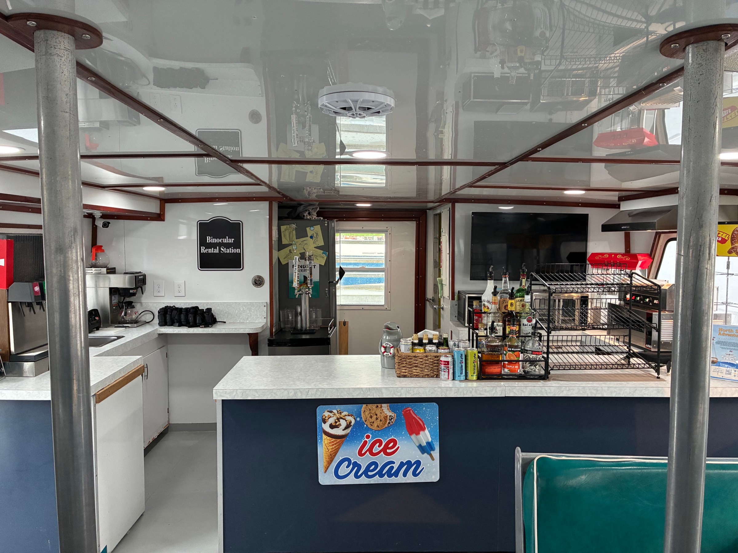 Boat interior with counter, ice cream sign, and various kitchen appliances.