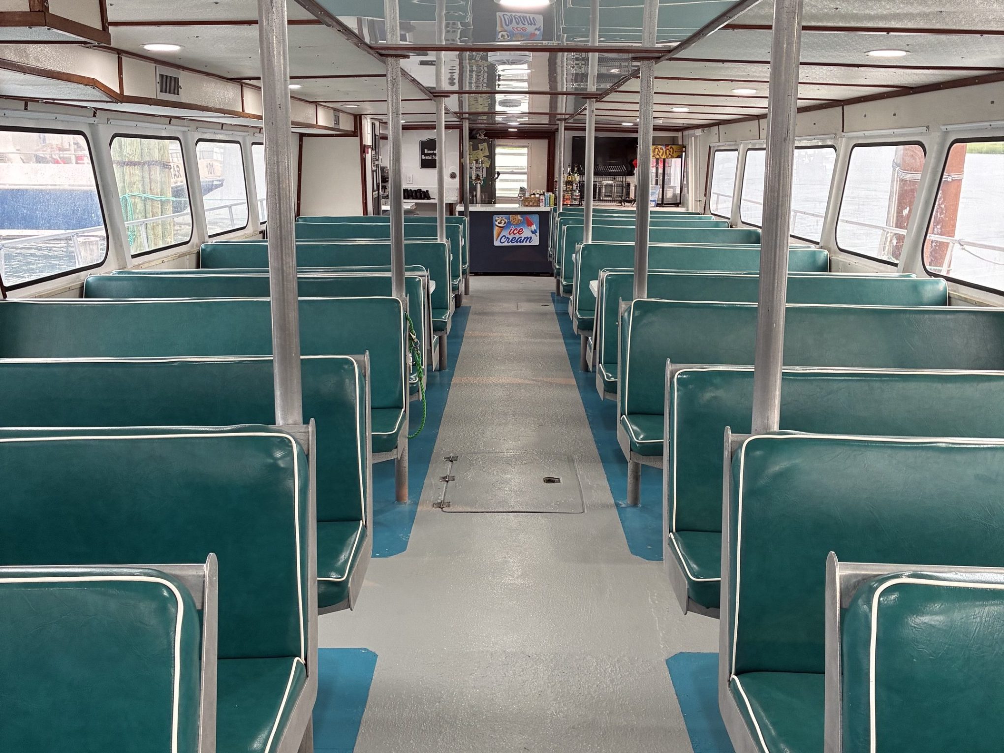 Empty bus interior with green seats and white aisle.