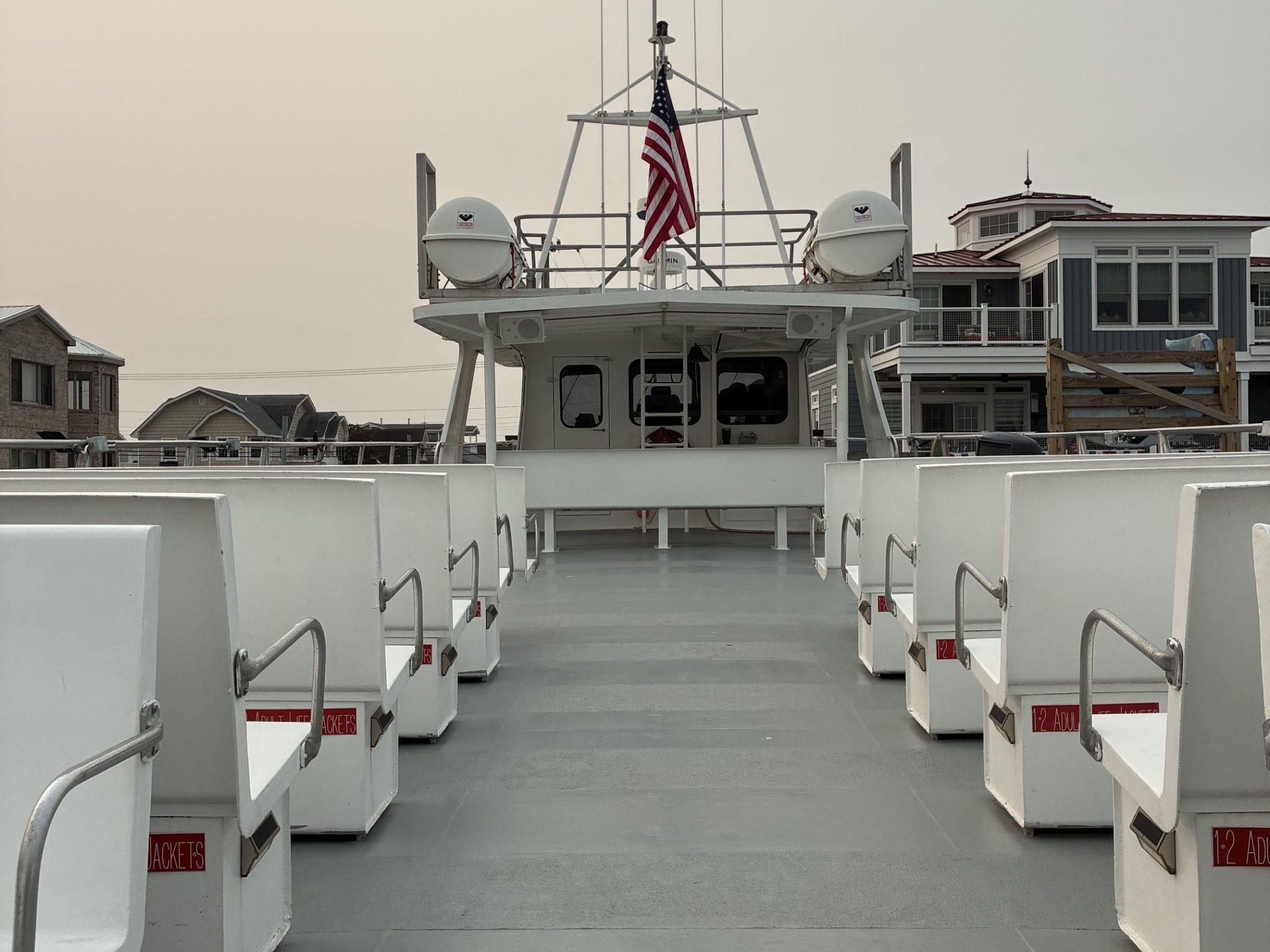 Empty deck of a ferry boat with benches, American flag, and calm sky.