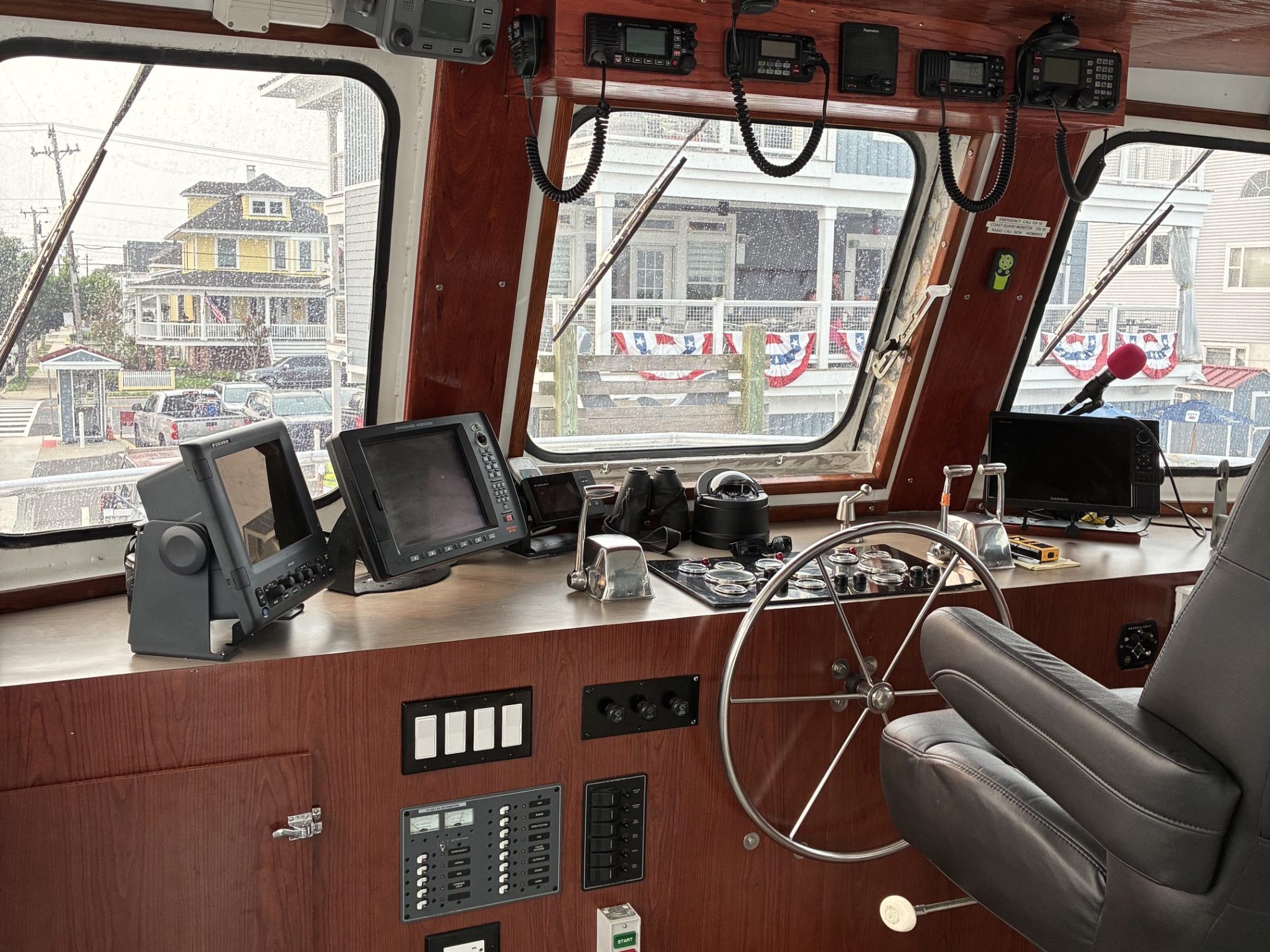 Boat cockpit with controls, steering wheel, and navigation screens.