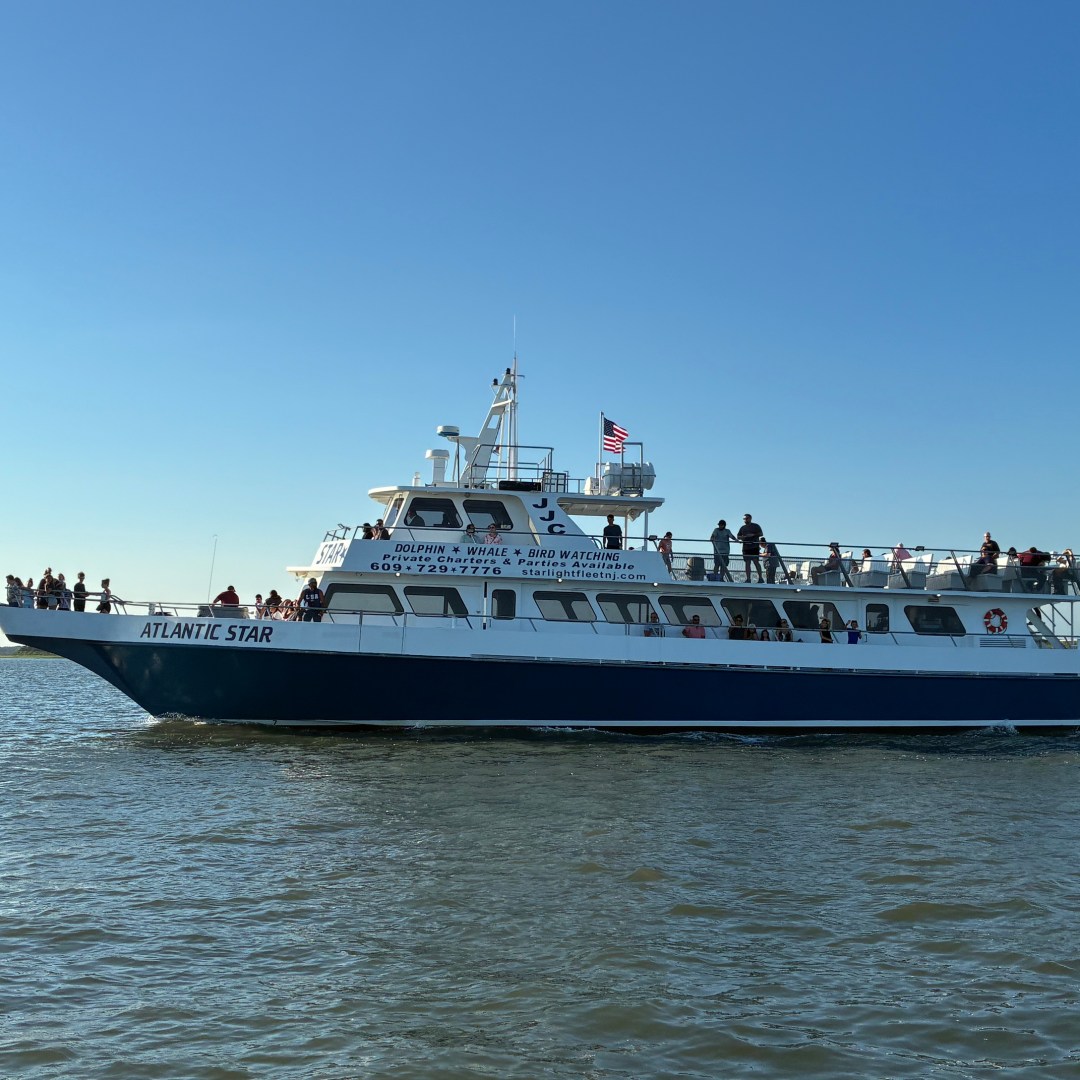 Large boat named 'Atlantic Star' on calm water under a clear blue sky.
