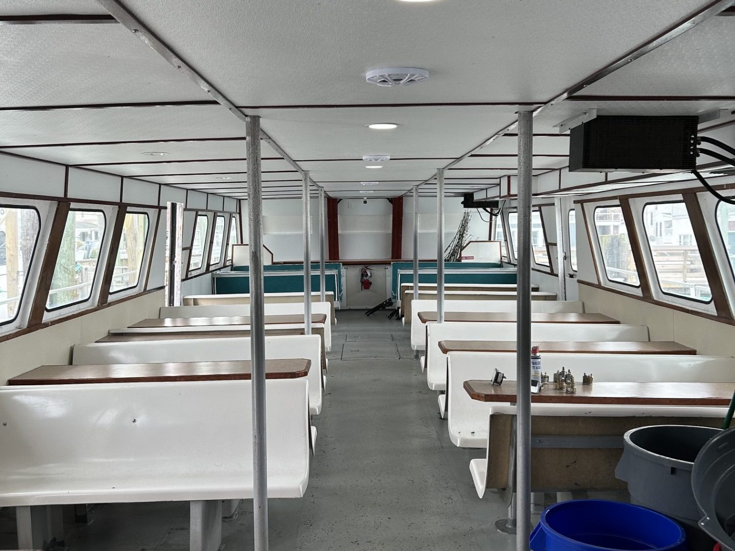 Interior of a passenger boat with benches and windows, view from front to back.