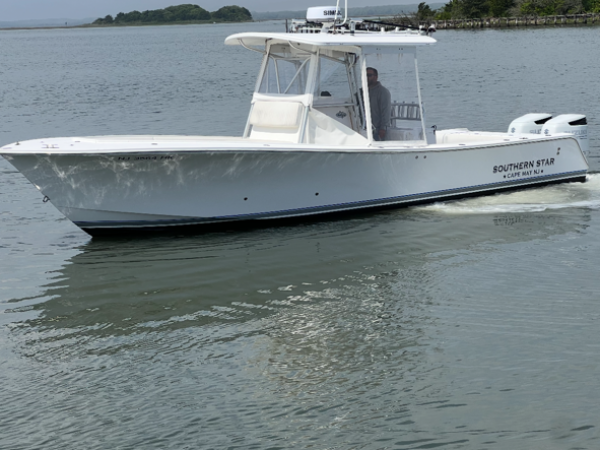 White boat named 'Poker Face' on calm water near shore.