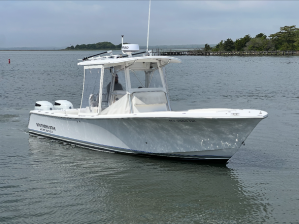 White motorboat on calm water near shoreline.