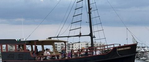 Silhouette of a tall ship sailing on the sea with cloudy sky.