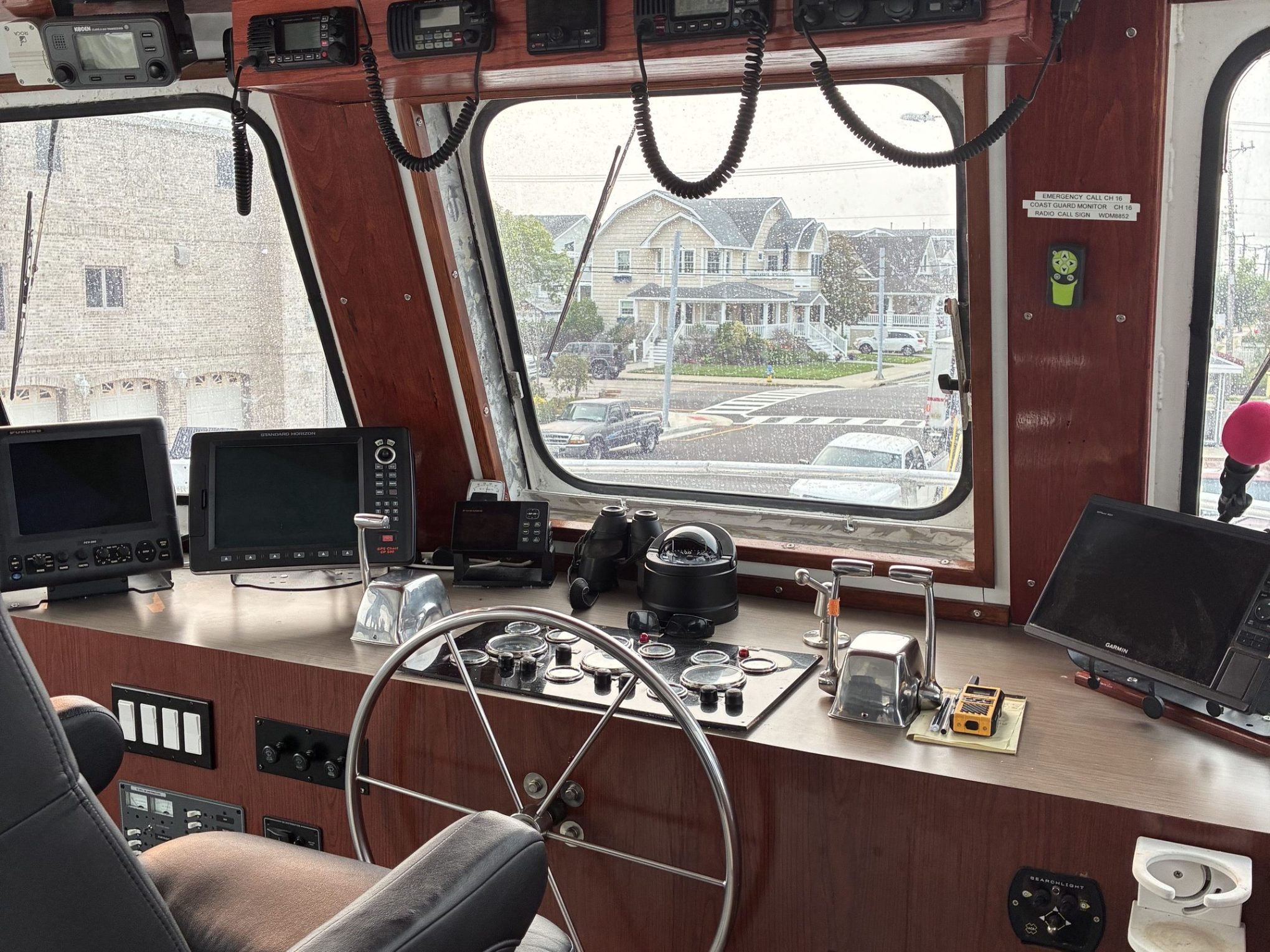 Wood-paneled ship cockpit with steering wheel and navigation equipment.