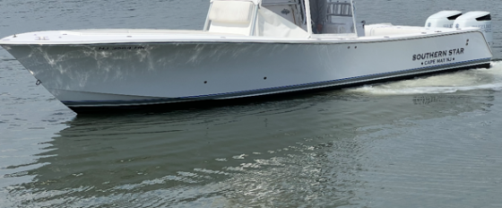 White motorboat on calm water with trees in the background.