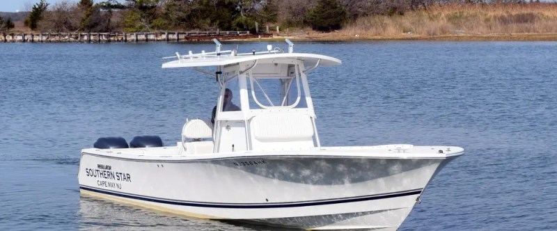 White powerboat named 'Southern Star' on calm water with trees in the background.