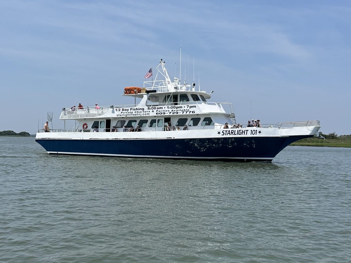 White passenger ferry on calm water with blue sky.